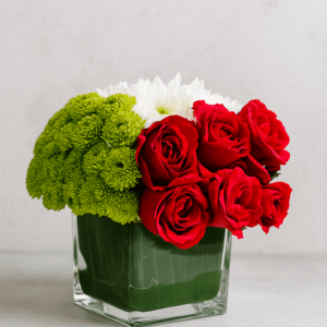 Small UAE National Day Flower Arrangement in a square glass cube with red roses, green button chrysanthemums, and white flowers.