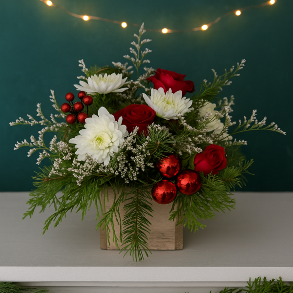 Christmas floral centerpiece with red roses, white mums, evergreen pine, and red ornaments in a rustic wooden box